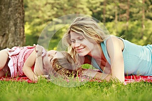 Young mother and her little daughter playing on grass