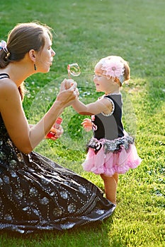 Young mother and her little daughter playing on grass