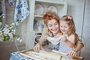 Young mother with her little daughter sculpt a dough