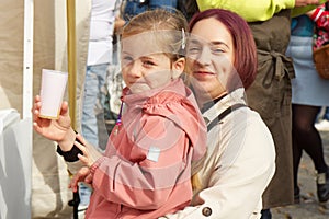 Young mother and her little daughter tasting drinks at Prague farmers market