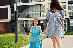 Young mother with her little daughter walking near the buildings