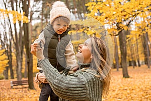 Young Mother with her little son in the autumn park have a fan. Yellow foliage, outdoor time with kids. Independent Happy Single