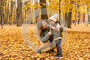 Young Mother with her little son in the autumn park have a fan. Yellow foliage, outdoor time with kids. Independent Happy Single