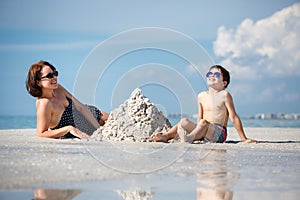 Young mother and her little son building sand castle at beach on Florida