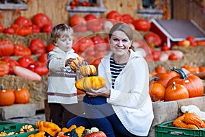 Young mother and her little son playing on pumpkin patch farm.