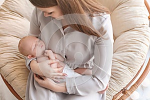 Young mother with her newborn baby in papasan chair