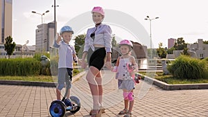 A young mother with her son and daughter ride a Segway and scooter in the Park.