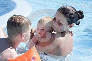 Young mother with her son and daughter smiling in swimming pool.