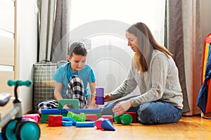 Young mother and her son playing together with colorful blocks