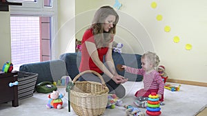 Young mother and her toddler girl playing together with toys at home.