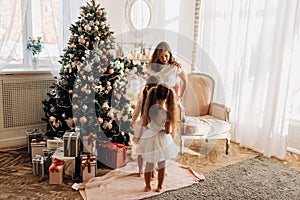 Young mother and her two charming daughter in nice dresses stand