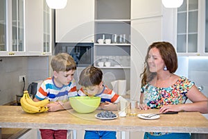 Young mother and her two kids at kitchen baking cookies