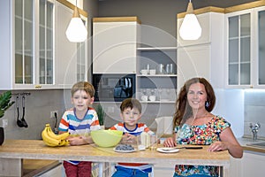 Young mother and her two kids at kitchen baking cookies