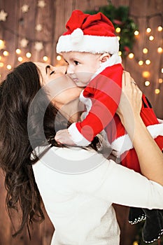 Young mother holding baby in santa suit