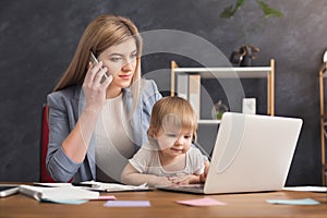 Young mother holding baby while talking on phone