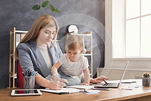 Young mother holding baby while writing notes