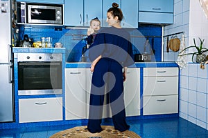 Young mother holding cute baby daughter in kitchen. Happy family mother and baby toddler girl cooking food at home