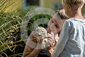 Young mother holding furry cute baby pet rabbit