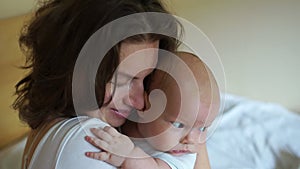 Young mother holding her baby in the bedroom. A woman carefully embraces a three-month-old baby. Mothers Day