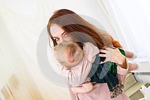 Young mother is holding her little daughter in hands. Maternal hugs