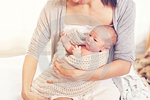 Young mother holding her newborn baby girl, one week daughter