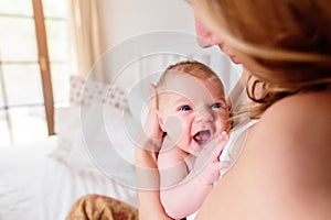 Young mother holding her newborn baby son, home bedroom