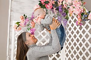 Young mother holding her newborn child. Mom nursing baby. Woman and new born boy in the room. Mother playing with