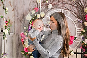 Young mother holding her newborn child. Mom nursing baby. Woman and new born boy in the room. Mother playing with