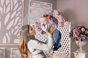 Young mother holding her newborn child. Mom nursing baby. Woman and new born boy in the room. Mother playing with