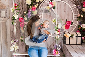 Young mother holding her newborn child. Mom nursing baby. Woman and new born boy in the room. Mother playing with