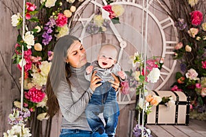 Young mother holding her newborn child. Mom nursing baby. Woman and new born boy in the room. Mother playing with