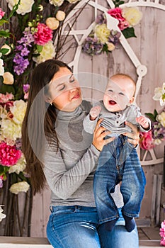 Young mother holding her newborn child. Woman and baby boy relax in a white bedroom. Nursery interior. Family at home