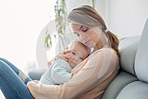 Young mother, holding her sick toddler boy, hugging him at home