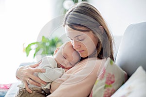 Young mother, holding tenderly her newborn baby boy