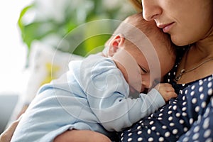 Young mother, holding tenderly her newborn baby boy