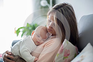 Young mother, holding tenderly her newborn baby boy