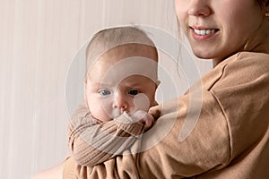 A young mother holds a child girl who is 3 months old. The brooding child in his mother`s arms looks into the camera