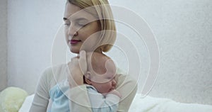 Young mother holds and cradles her crying baby on hands at home.