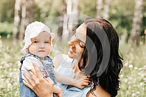 A young mother holds the little daughter of the infante in the park in the summer