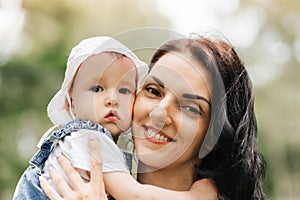 A young mother holds the little daughter of the infante in the park in the summer