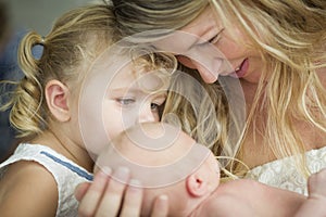 Young Mother Holds Newborn Baby Girl as Young Sister Looks