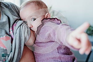 young mother at home breast feeding her adorable one year old baby girl. family time