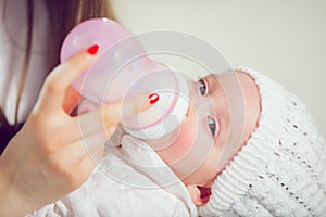 Young mother at home feeding their new baby girl