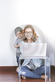 Young mother in home office with computer and her son