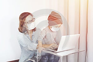 Young mother in home office with computer and her son