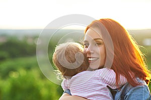 Young mother hugging child, smiling on beatiful panoramic view behind.