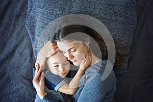 Young mother, hugging her child in bed, positive emotion, love, happiness, peace