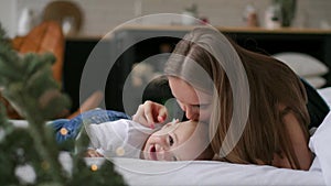 Young mother hugging her newborn child. Mom nursing baby. Woman and new born boy relax in a white bedroom. Family at