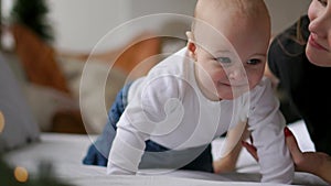 Young mother hugging her newborn child. Mom nursing baby. Woman and new born boy relax in a white bedroom. Family at