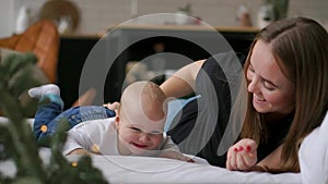 Young mother hugging her newborn child. Mom nursing baby. Woman and new born boy relax in a white bedroom. Family at
